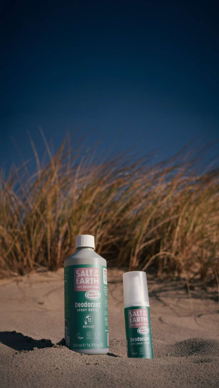Salt of the Earth natural deodorant and refill bottle in melon & cucumber scent, photographed on a UK beach at sunset