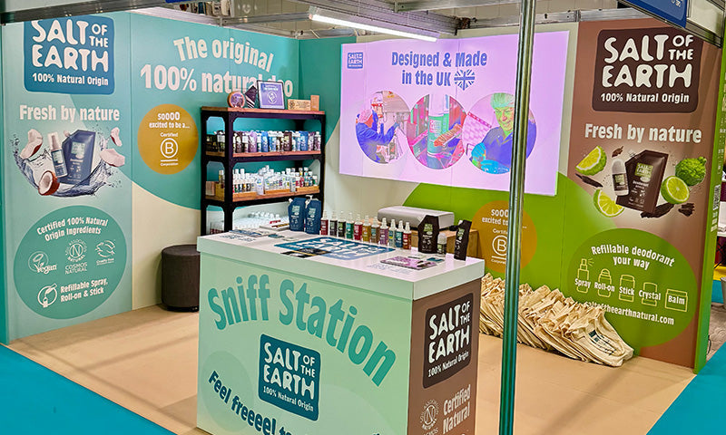 Salt of the Earth completed exhibition stand at NOPE 2025, featuring cardboard display panels, our sniff station, product shelving, certification logos, and 100% natural origin messaging alongside our B Corp certification.