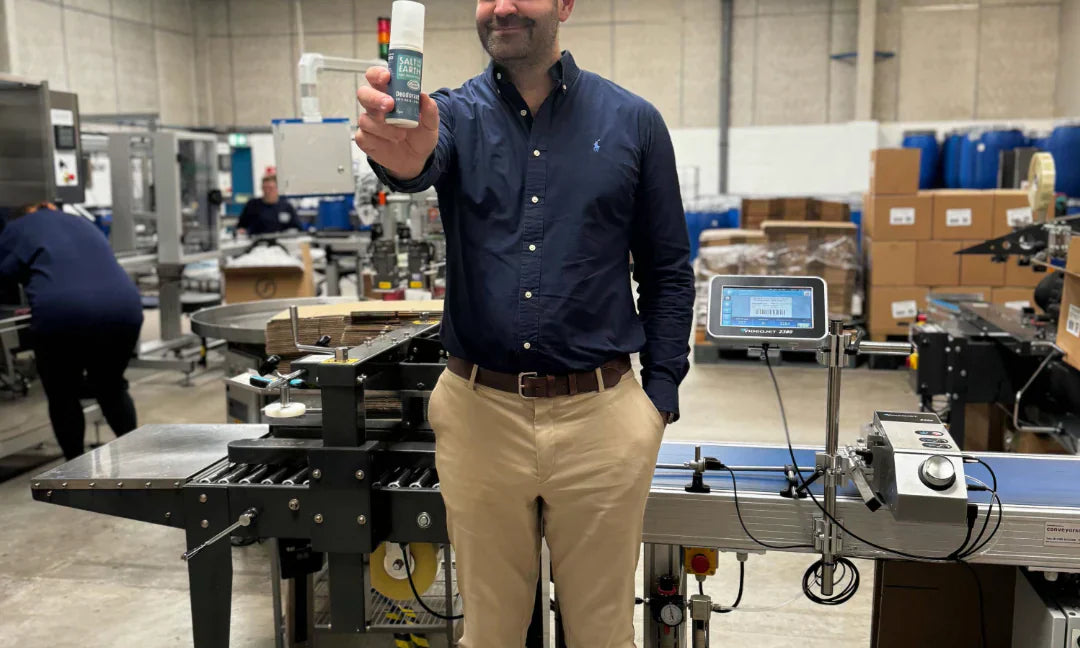 Thomas Laird, MD of Salt of the Earth, holding Ocean & Coconut natural deodorant spray at the end of production line