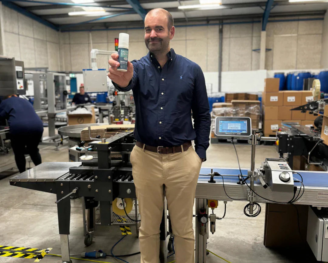 Thomas Laird, MD of Salt of the Earth, holding Ocean & Coconut natural deodorant spray at the end of production line