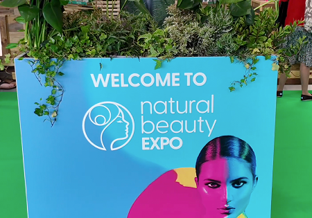 Empty Salt of the Earth natural deodorant exhibition stand F20 at Natural Beauty Expo before setup, showing the white shell scheme booth with blue branded header panels.